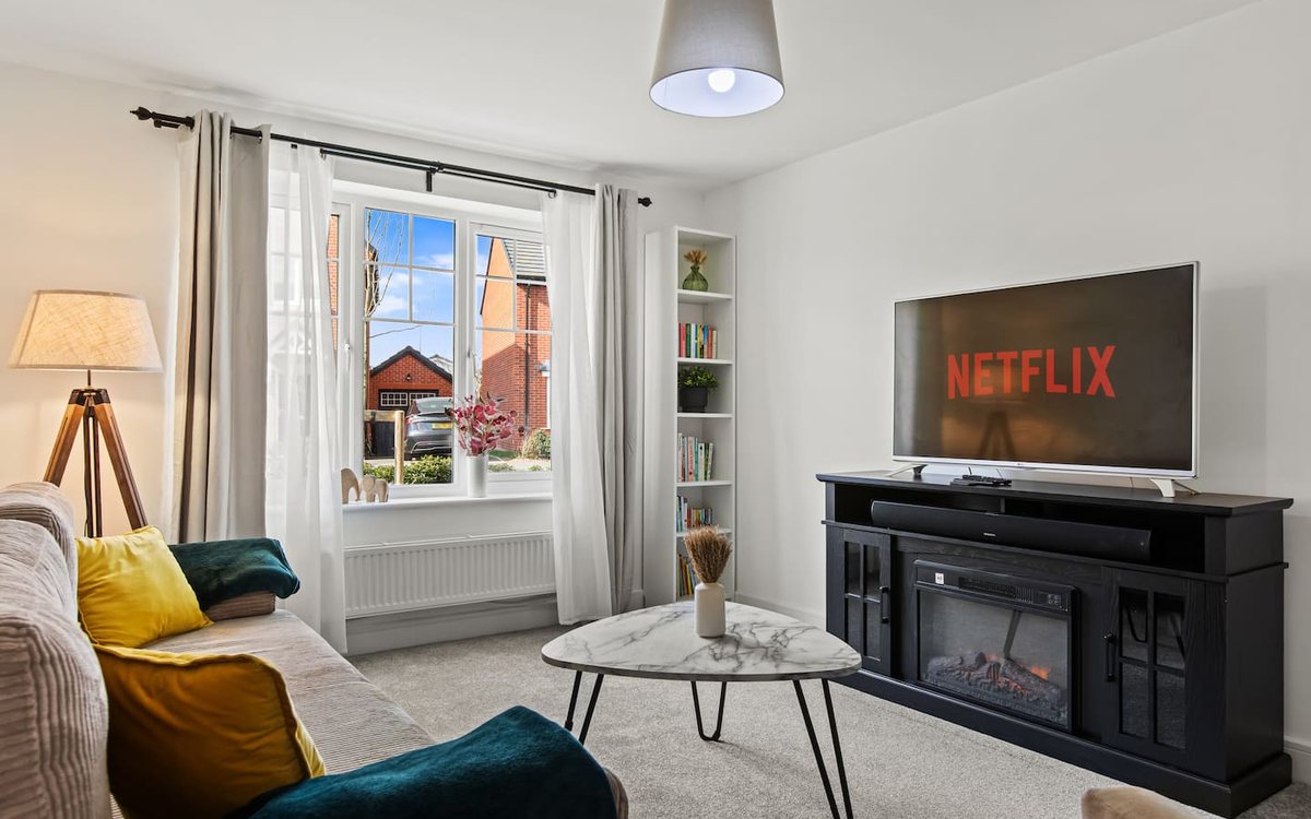 Bright living room with a cream corner sofa and a wide electric fireplace &mdash; Neptune House, a Gales-managed contractor let in Chester